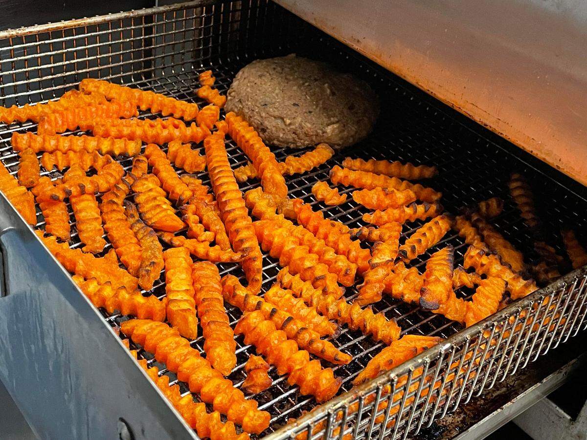 An oat patty and freshly cut sweet potato fries in an air fryer at Verus Vine Plant Based Kitchen in Byron.