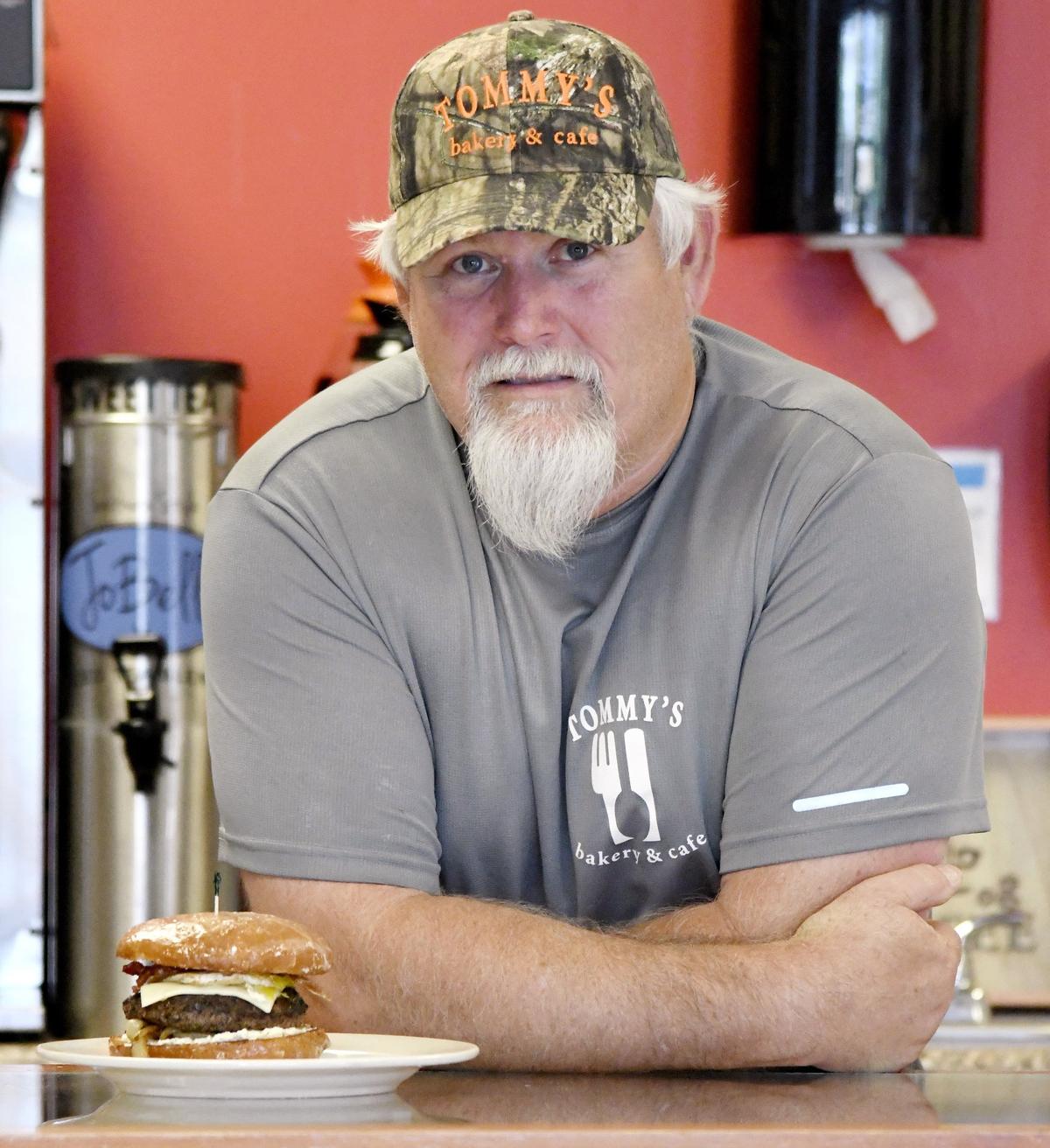 Tommy Sadler, owner of Tommy’s Bakery & Cafe, showing off one of his locally renowned Donut Burgers in 2018.