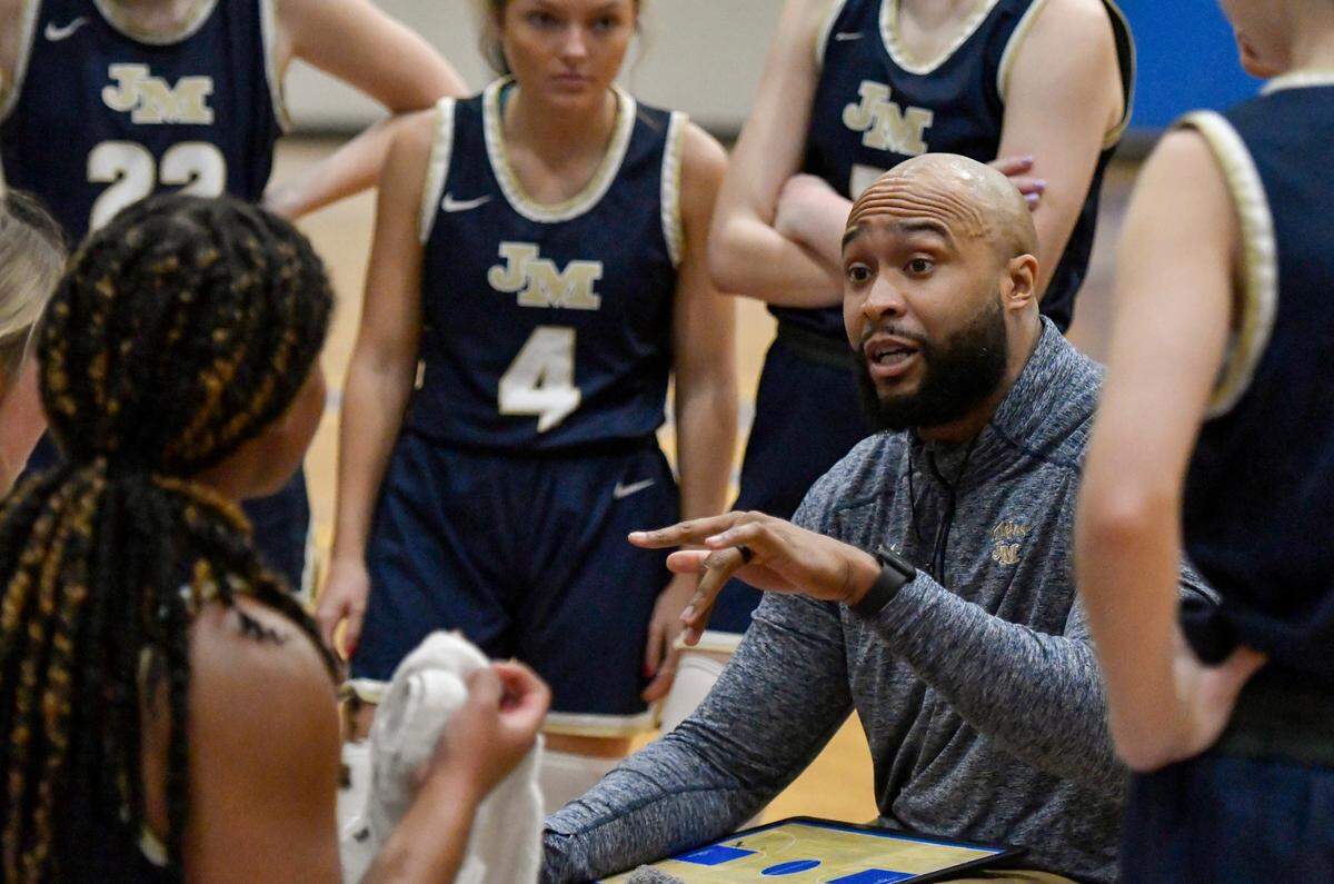 John Milledge coach Jeremy Mayweather speaks with his team during a timeout of the Trojans’ 57-47 win over FPD in their region tournament Thursday.