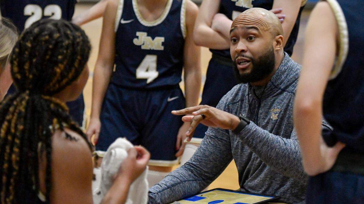 John Milledge coach Jeremy Mayweather speaks with his team during a timeout of the Trojans’ 57-47 win over FPD in their region tournament Thursday.