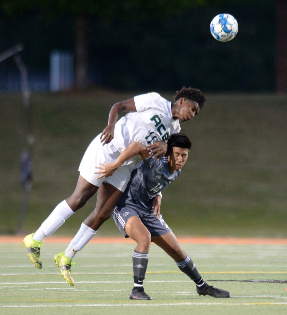 ACE midfielder John Haithcock (11) heads the ball over GMC striker Ethan Tolentino (14) during their GHSA 1A State Championship match Friday night at Mercer.