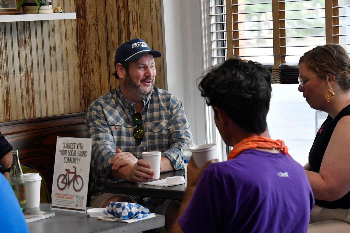 Bobby Schorr, owner of Bike Tech in Macon, speaks with other Car Free Day meetup attendees on Friday, May 24, 2024, at Macon Bagels in Macon, Georgia. Macon Car Free Day is an annual event sponsored by Bike Walk Macon that encourages alternative transportation throughout the city.