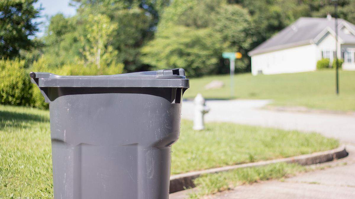 A trash can sits on the curbside ready for collection