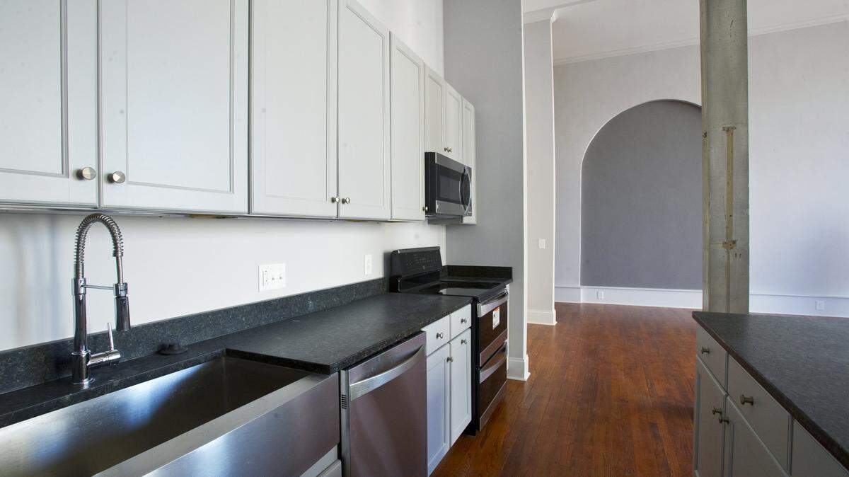 The brushed stainless steel appliances blend seamlessly with the subtlety of the cabinet finishes and the contrasting gray of the niche in the background.