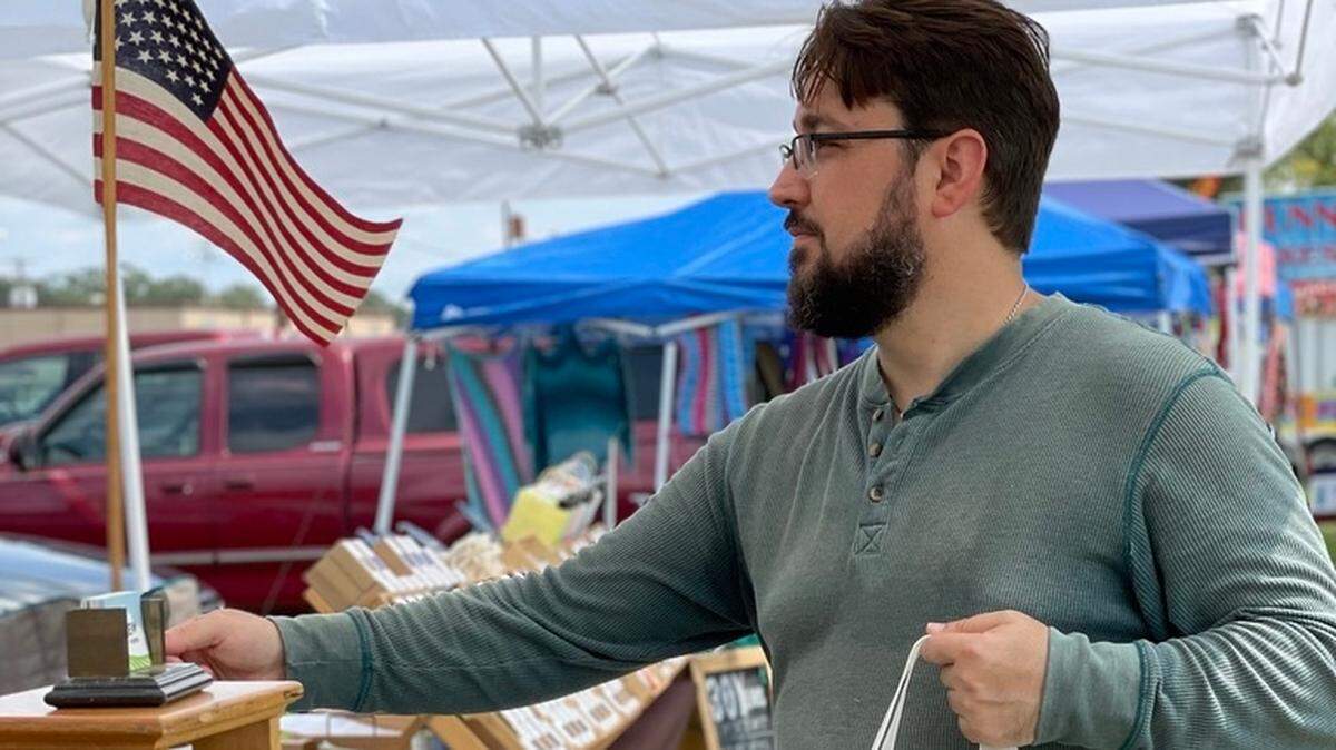 Joshua Hess, owner of the International City Farmers Market in Warner Robins, bags food for a customer. Hess used revenue from this business The Sassy Alpaca to purchase the market and help feed the homeless.