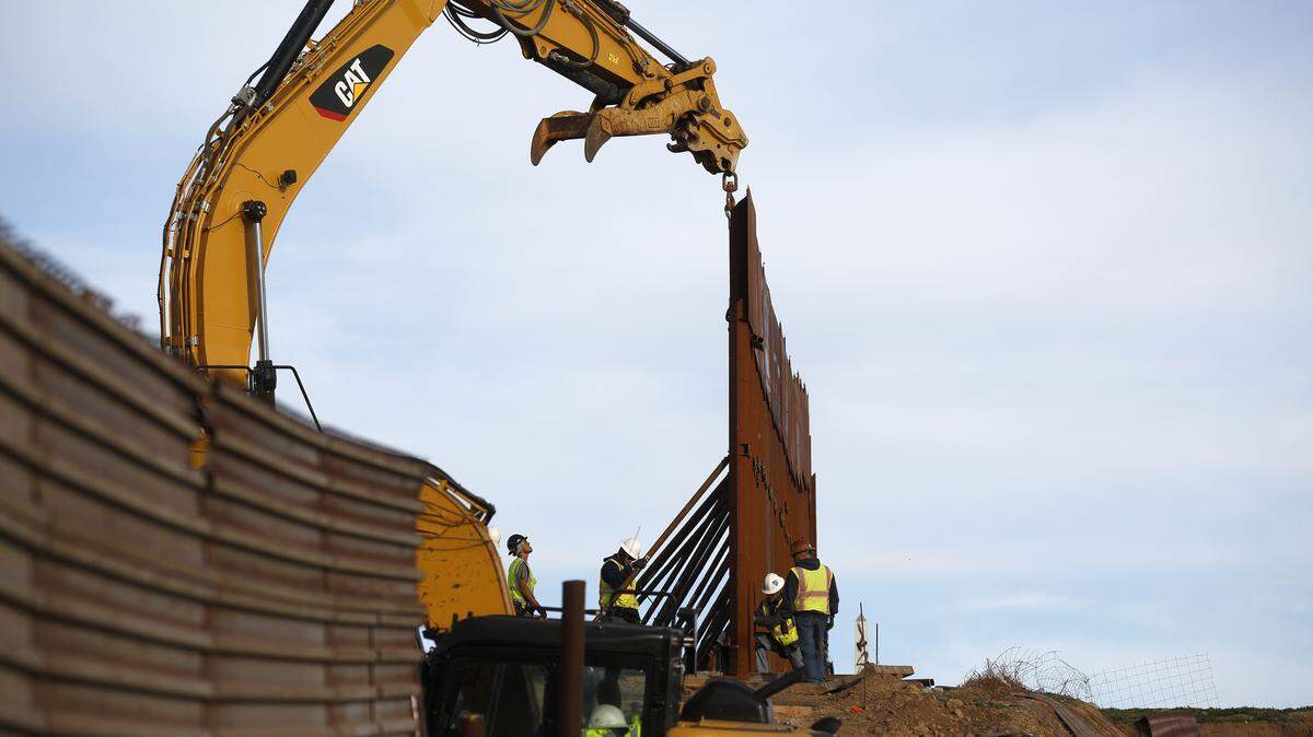 Workers replace sections of a wall on the U.S.-Mexico border, left, with new sections, right, in 2018.