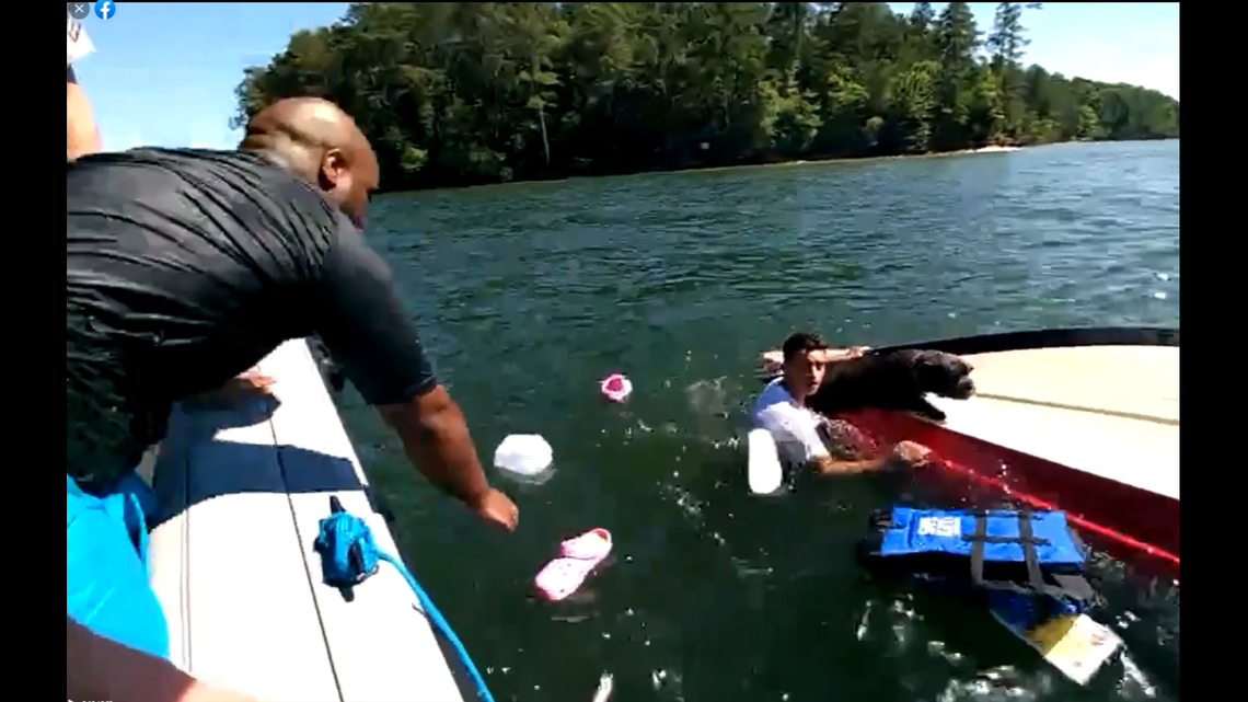 A man holds a dog atop the capsized boat as he waits to be rescued from Lake Allatoona.
