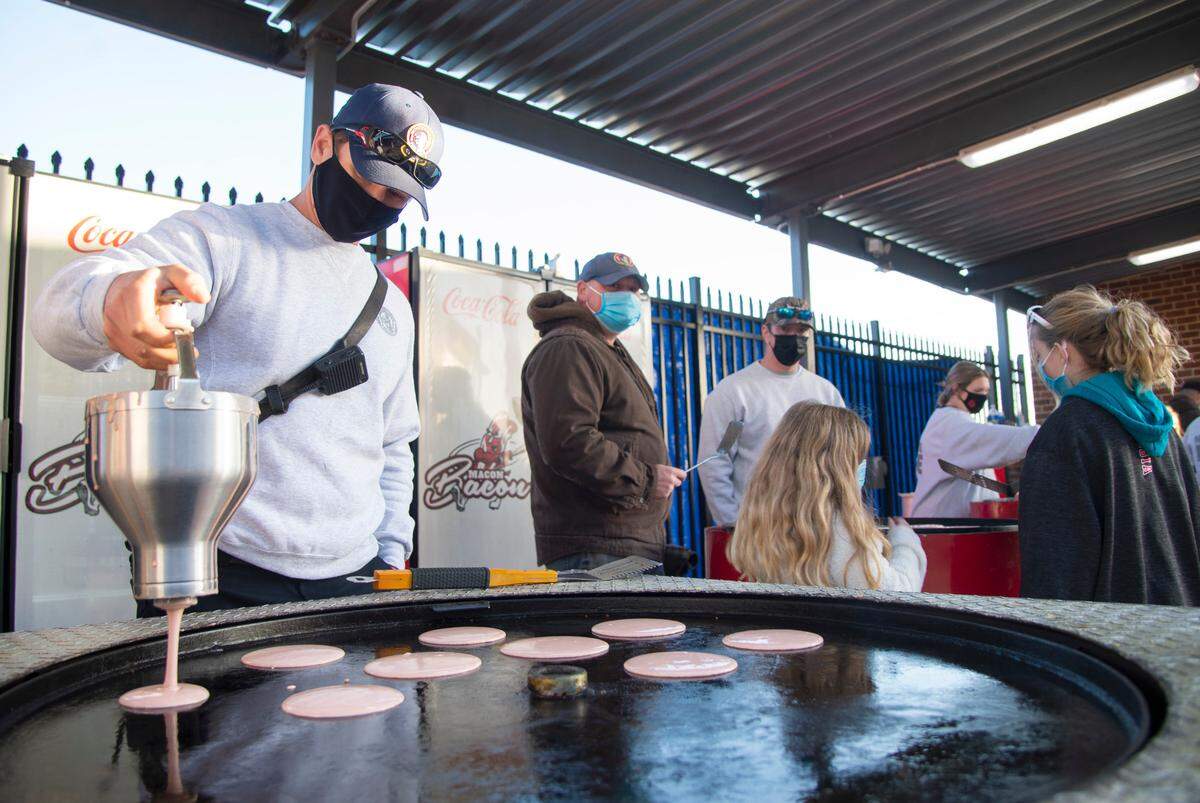 A member of the Macon-Bibb County Fire Department drops pancakes onto a rotating griddle Saturday morning during the Cherry Blossom Festival Pink Pancake Breakfast at Luther Williams Field.