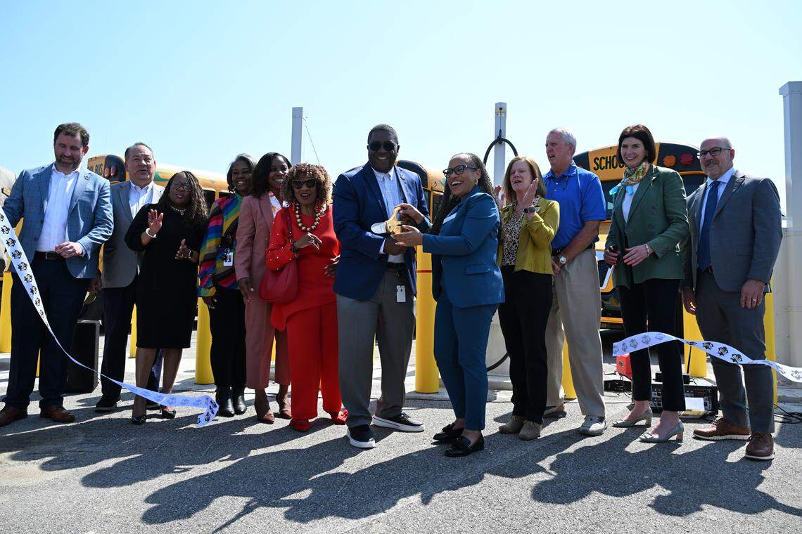 Bibb County School District officials and other stakeholders cut a ceremonial ribbon to unveil 15 all-electric Bibb County School District buses on Thursday, April 23, 2026, at the district bus depot in Macon, Ga. The vehicles are the first all-electric buses in the district’s fleet. Thursday’s unveiling included 15 buses and chargers, along with 10 propane-powered buses.