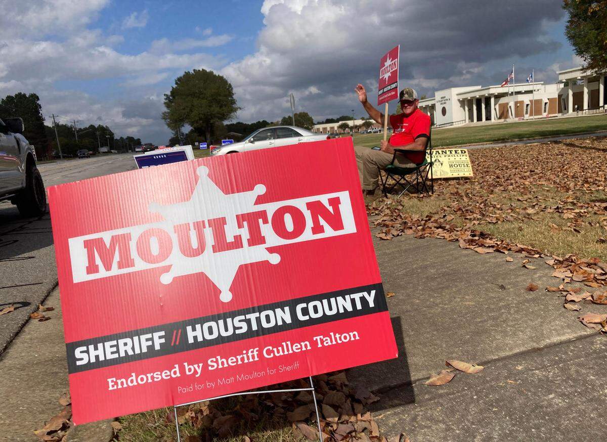 Off-duty Houston County sheriff’s Sgt. Doug Blackmon, holding an election sign for Matt Moulton for Houston County sheriff, waves Tuesday afternoon, Nov. 5, 2024, outside the Houston County Annex polling place.