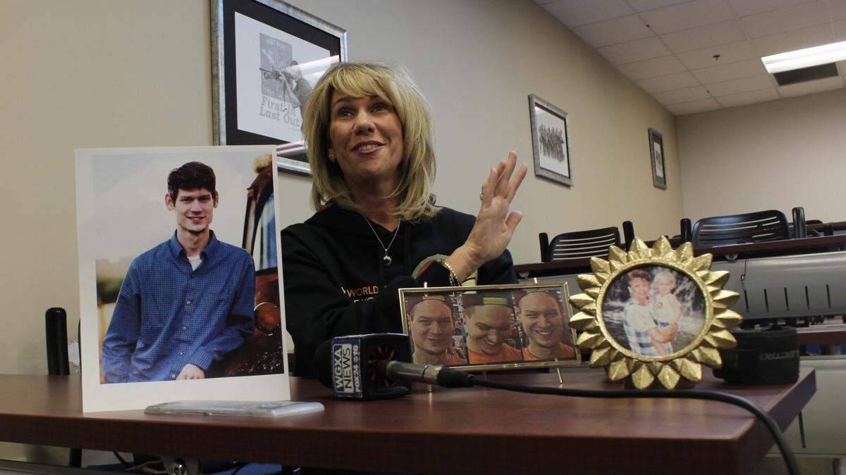 Leah Maas showed framed photos of her son, Parker Moore, to journalists, Warner Robins Police Chief Wayne Fisher and Lt. Justin Clark, at a press conference on Thursday, Nov. 13, 2025, at the Warner Robins Police Department at 100 Watson Boulevard. Maas recalled positive memories about Moore, but she was upset that investigators did not yet solve the 2018 homicide of her son.
