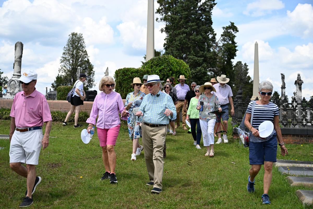 Jim Barfield walks to the next plot and talks with ramble attendees during his Rose Hill Ramble on Sunday, April 27, 2025, in Rose Hill Cemetery in Macon, Georgia. Barfield led a group of around 50 people through parts of the cemetery in an hour and a half tour.