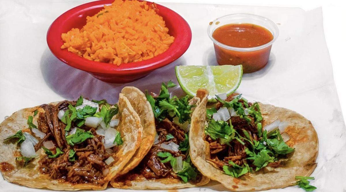 Tacos de birria from El Metate Mexican Restaurant. The dish is described on the menu as corn tortillas with birria meat. Served with onion and cilantro.