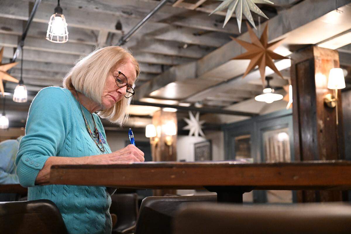 Macon-Bibb County Democratic Committee treasurer Lynn Snyder writes a postcard to Middle Georgia state representatives at the New Voices, Better Choices post carding event on Tuesday, Nov. 18, 2025, at Just Tap’d Macon in Macon, Georgia. The event focused predominantly on advocating for mayoral term limits in Macon.