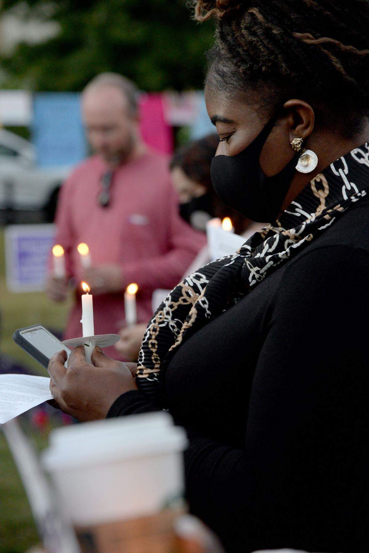 Canetra Ford, a victim advocate at the District Attorney’s office, looks at her candle at a candlelight vigil for Domestic Violence Awareness Month in Rosa Parks Square.