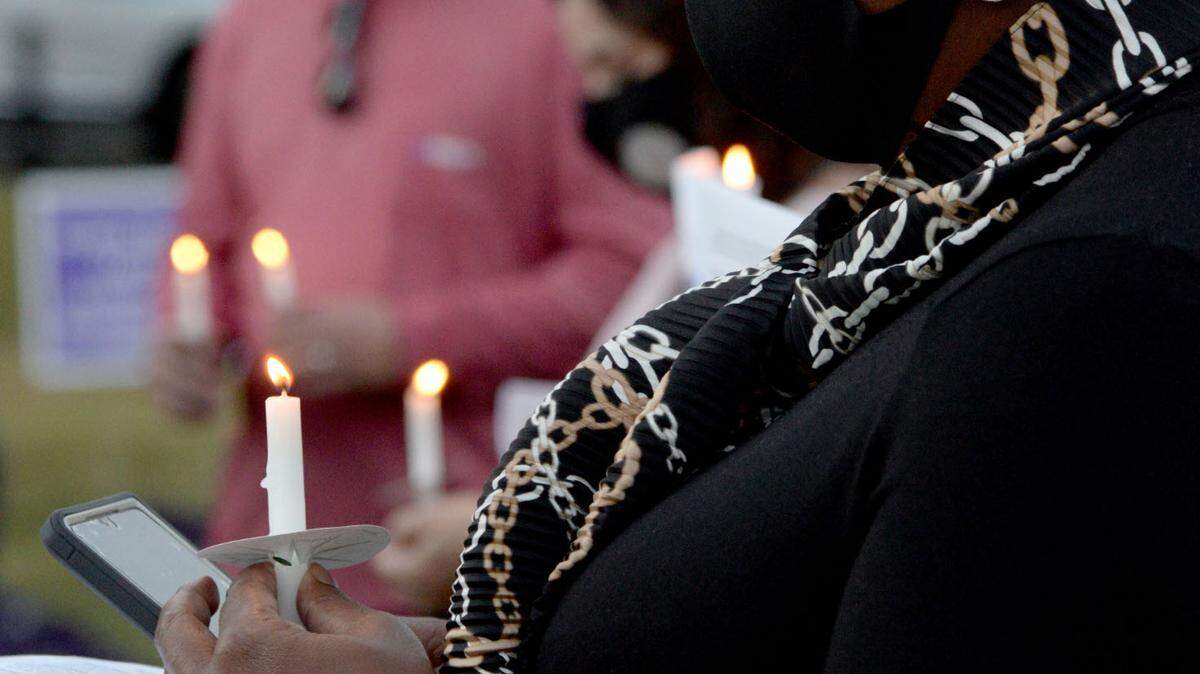 Canetra Ford, a victim advocate at the District Attorney’s office, looks at her candle at a candlelight vigil for Domestic Violence Awareness Month in Rosa Parks Square.