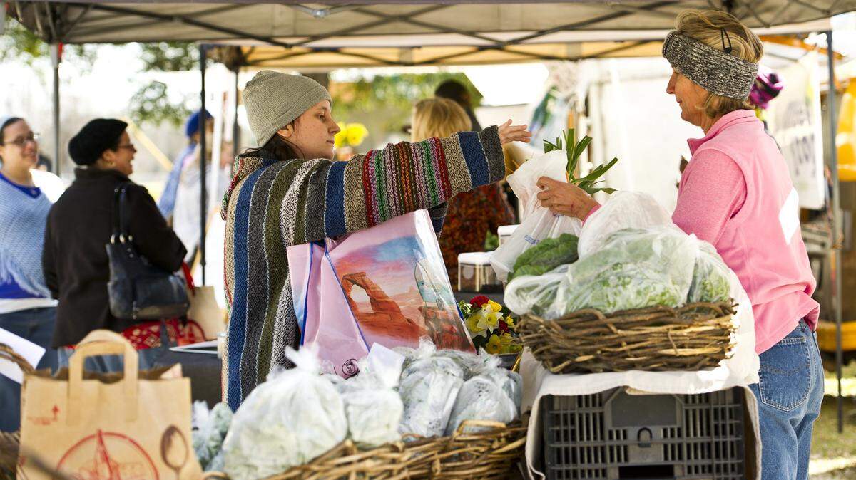Katherine Maxwell buys carrots and garlic from new International City Farmers' Market vendor Kaye Smith, of Vesterfield Farms.