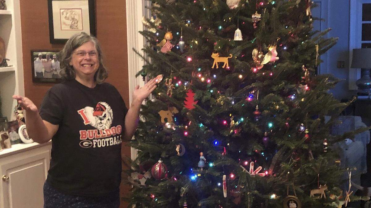 Merrie Kaplan stands beside a family Christmas tree.