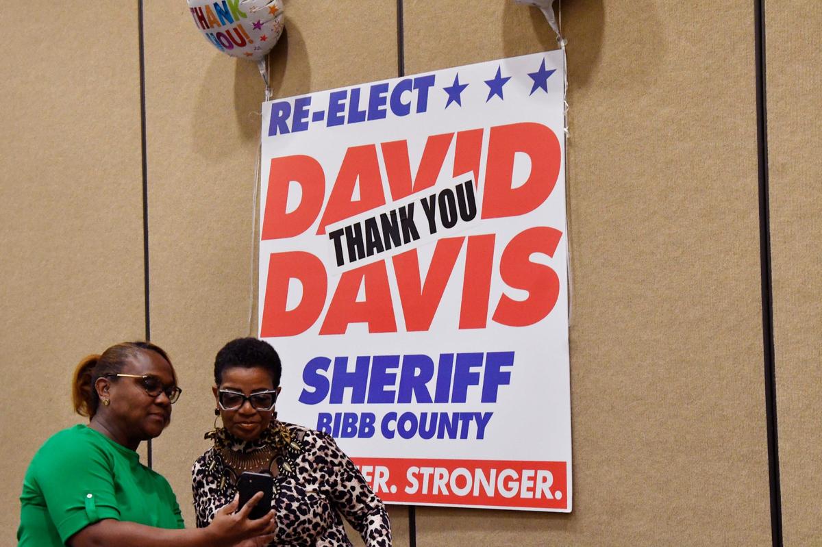 Lieutenant Linda Howard (left) and Debra Rhodes look at a photo taken in front of the David Davis reelection poster on Thursday, May 30, 2024, at the Edgar H. Wilson conference center in Macon, Georgia. Davis held the event to commemorate his reelection into a fourth consecutive term as Bibb County Sheriff.
