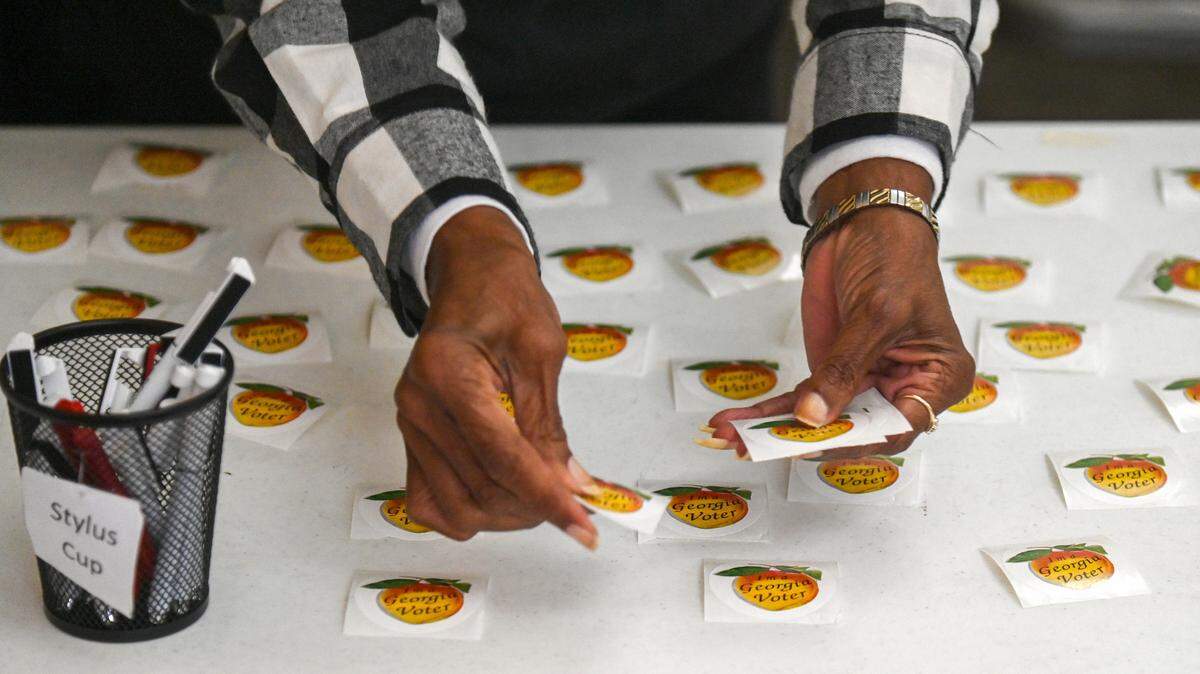 Poll officer Patricia Daniely places stickers on a table near the exit as voters cast their ballots at St. Francis Episcopal Church on Forest Hill Road.