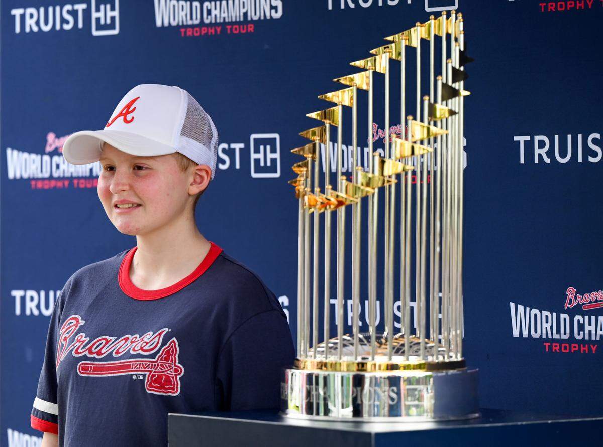 Gracie Thigpen, 13, has her photo taken with the Atlanta Braves 2021 World Series Trophy outside of Beverly Knight Olson Children’s Hospital Tuesday morning. Thigpen is a patient at the hospital fighting leukemia.