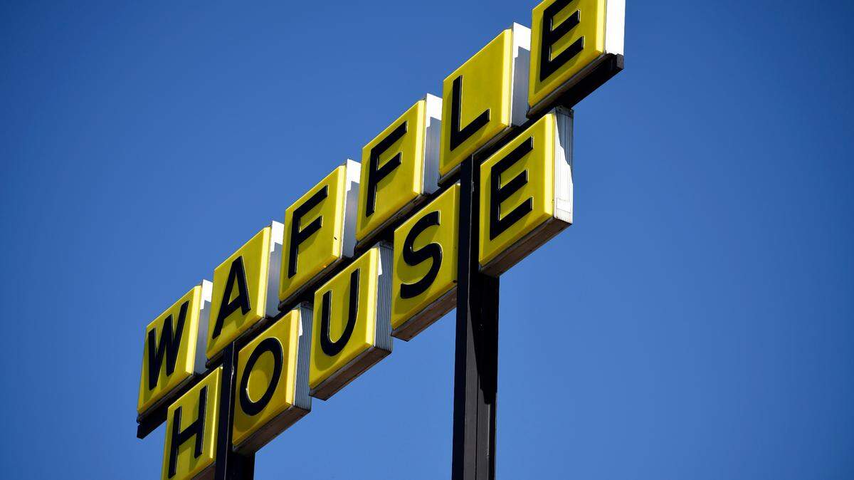 Signage is posted on the inside window of a Waffle House restaurant
