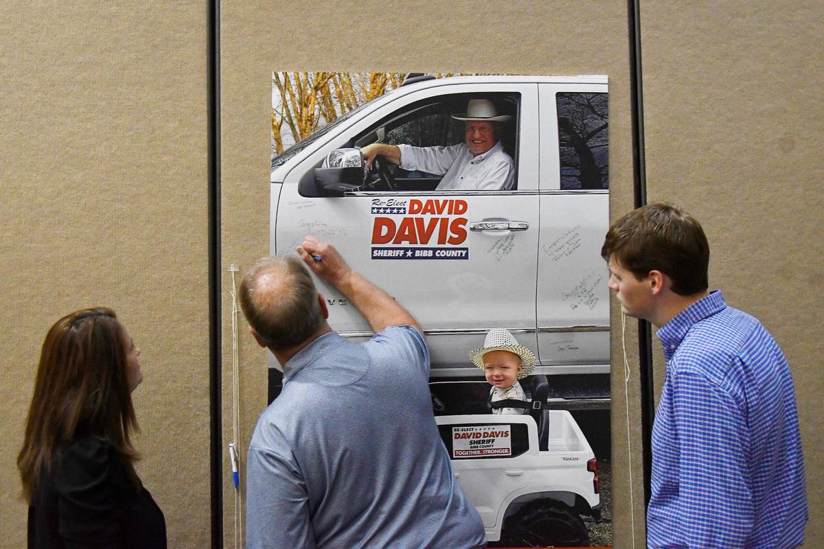 Reelection celebration attendees sign a poster showing Bibb County Sheriff David Davis and his grandson on Thursday, May 30, 2024, at the Edgar H. Wilson conference center in Macon, Georgia. Davis held the event to commemorate his reelection into a fourth consecutive term as Bibb County Sheriff.