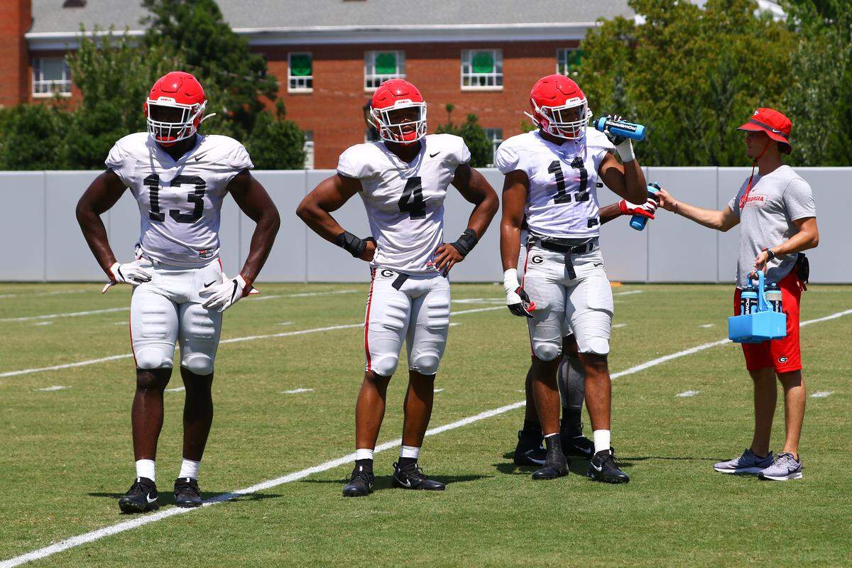 Georgia outside linebackers Azeez Ojulari (13), Nolan Smith (4), and Jermaine Johnson (11) take a break during the Bulldogs’ session on the Woodruff Practice Fields in Athens, Ga., on Thursday, Aug. 8, 2019.