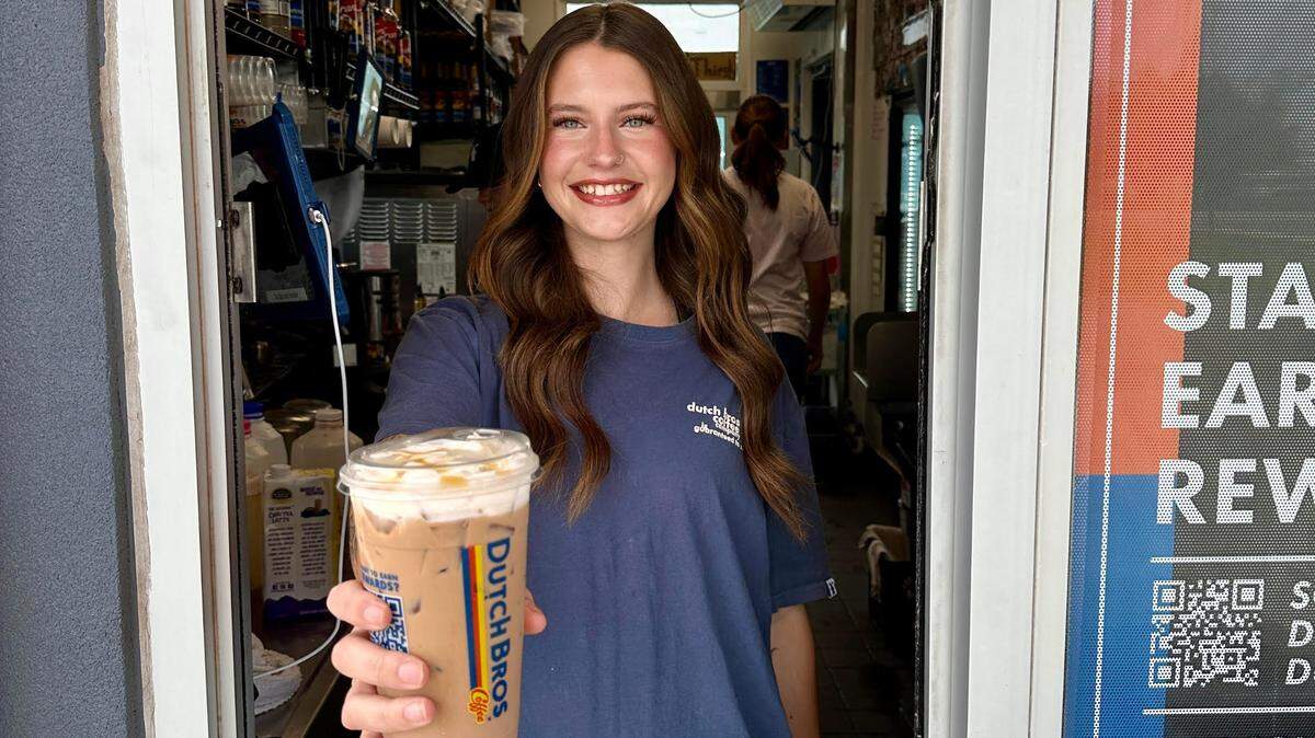 Maggie Briggs, the new regional operator for the Dutch Bros Coffee to open this summer in Warner Robins, holds up her favorite “mafia style” iced “carmelizer” with a soft top and caramel drizzle at another store in Tulsa, Oklahoma.