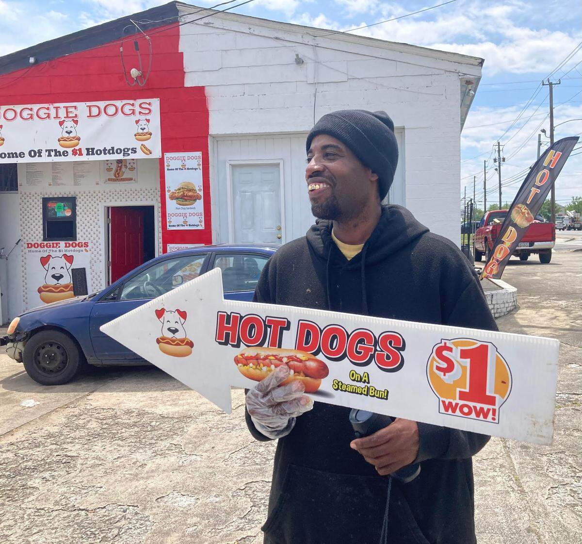 In this Telegraph photo taken in April, Doggie Dogs owner Tony Walker outside his walk-up hot dog joint off Pio Nono Avenue in Macon with a sign offering plain hot dogs for $1.