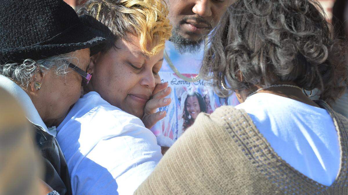 Tonora Jones, center, the mother of 14-year-old Ta'shuntis "Tootie" Roberts, is comforted as she waited to enter Southwest High School Friday where members of the marching band celebrated her life and mourned her death. Roberts was killed in a spray of gunfire directed at her south Macon home. Investigators continue to find the two men linked to Sunday night's drive-by shooting.