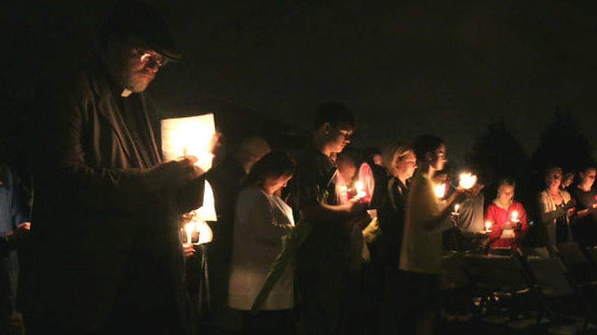 Father Eric Filmer of St. Patrick´s Catholic Church in Kathleen, left, stands with mourners at the vigil for slain teenager Ryan Skeen at Veterans High School in Kathleen. Sheen's accused killer, Kaden Barefoot, 13, will be tried as an adult for the murder. 