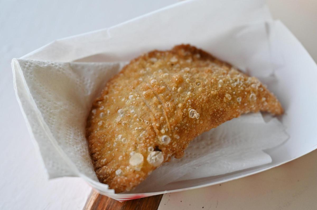 An empanada from Caribbean Queens Latin Cuisine sits on a table in restaurant on Thursday, March 27, 2025, in Forsyth, Georgia. Owner Lisa Morales collaborates with her downtown Forysth neighbor Treats with Lenise owner Lenise Leknes for homemade and fresh empanada dough.