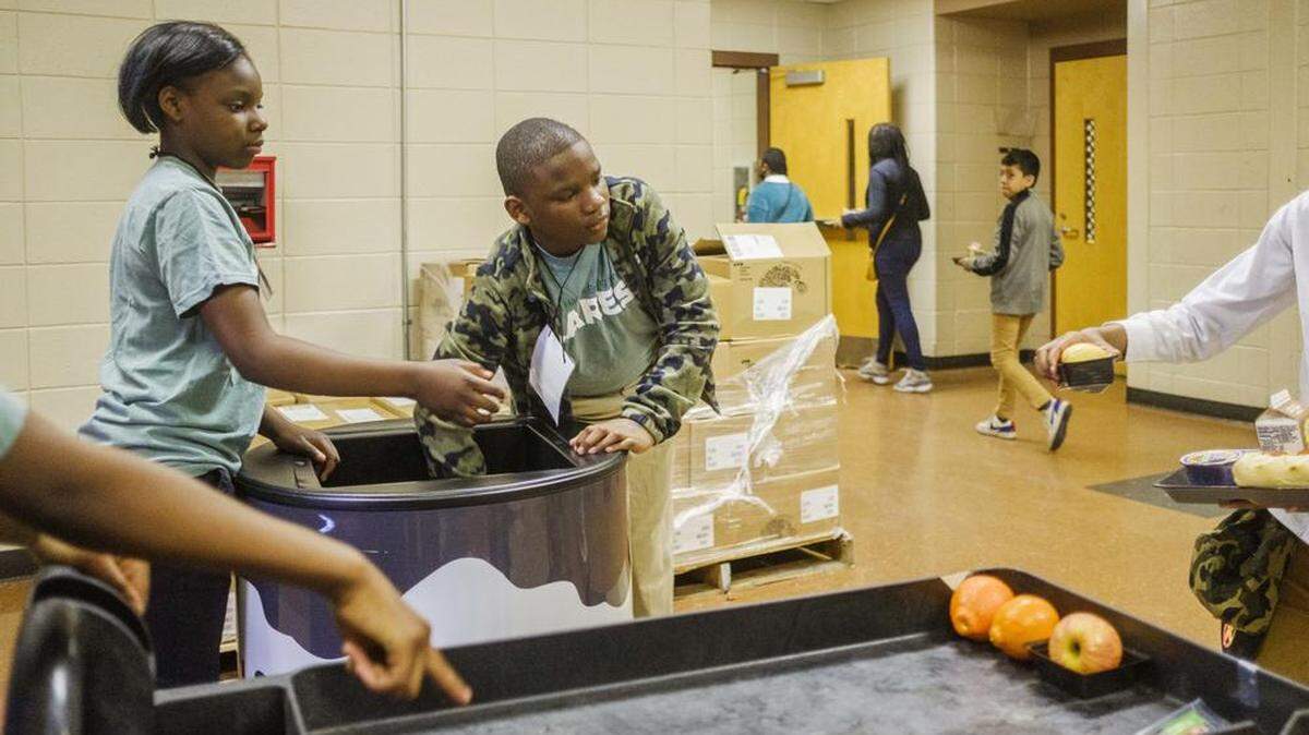 Ballard Hudson Middle School students Jalexia Maloy, left, and Jayden Parker, center, collect food during their lunch period in their roles as volunteer workers in the Helping Hands Ending Hunger program.