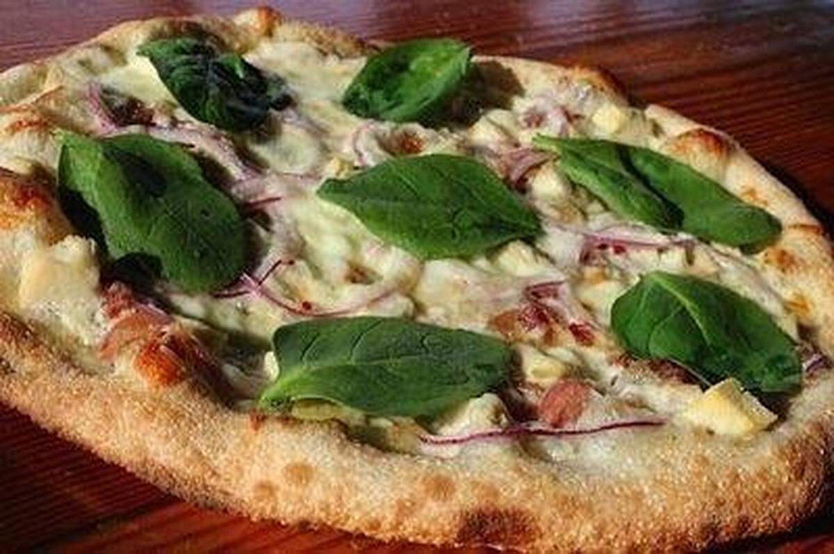 The “alfredo-licious” signature pizza from Smokin’ Oak Wood-Fired Pizza & Taproom. The pizza is made with alfredo sauce, mozzarella, applewood bacon, chicken, red onion and red pepper flakes, baked in the wood-fired oven and then topped with fresh spinach and cracked pepper, according to the menu.