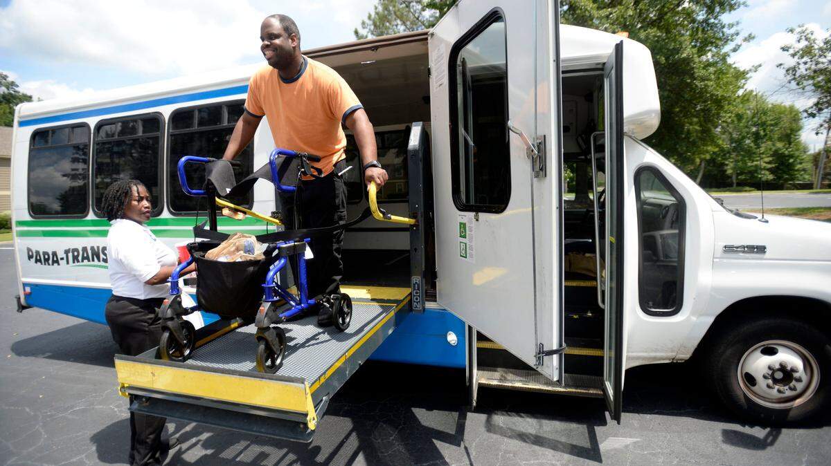 Para-transit driver Novella Smith, left, helps Jonathan Mercer get home from work Friday afternoon in west Macon. Macon transit buses are now expected to run next week except for the Fourth of July, Craig Ross, president and CEO of the Macon-Bibb County Transit Authority, said Saturday. But for how long remains uncertain as budget discussions continue.