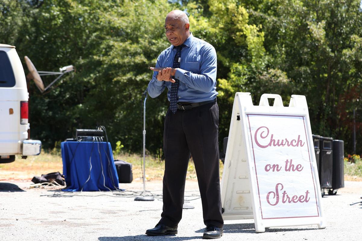 Pastor and retired counselor Prince Moon speaks to a live stream before the start of Church on the Street on Sunday, Aug. 25, 2024, on the side of Houston Avenue in Macon, Georgia. Moon’s church services aim to provide support for local people specifically to turn away from violence and find social support in other areas.