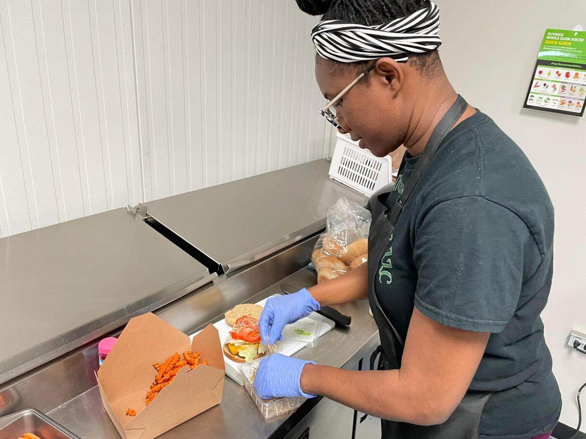 Lavellie Thomas, co-owner of the new Verus Vine Plant Based Kitchen in Byron, addes the finishing touches to a Verus power burger, an oat patty topped with sprouts, lettuce, tomato and onions and served with freshly sliced sweet potato fries. This one is minus the onions and add cheese made from cashews.