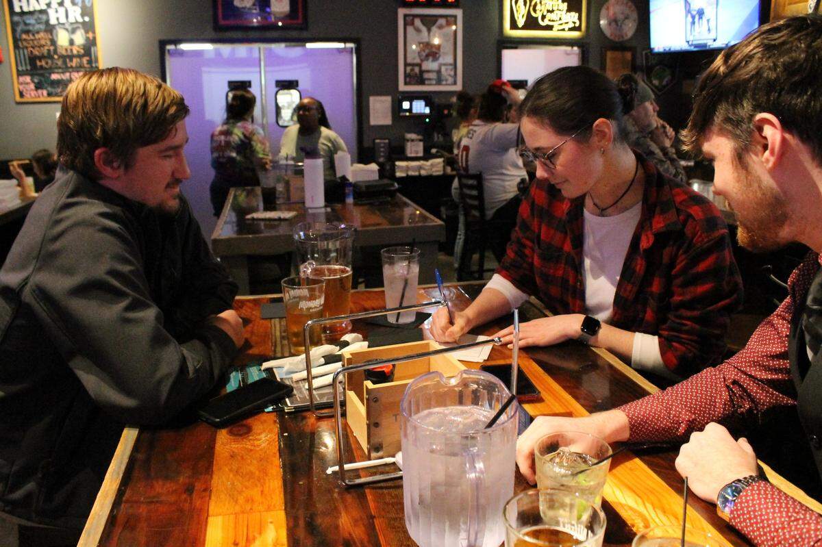 Chris Clisham (left), Jacqueline Palmer (middle) and Joshua Samosuk (right) fill in their trivia answer sheet at Amici on Feb. 11, 2025. Team Coconut Mall meets every week for deals on food and drinks and to play trivia.
