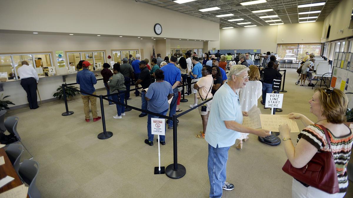 Polling place worker Michael Barron hands out sample ballots to voters coming to the Macon-Bibb County Board of Elections office around lunchtime Wednesday.  Elections supervisor Jeanetta Watson said at the height of the day it’s not uncommon for two to three dozen people to be waiting in the line to vote, but new software has streamlined the process. Most people can vote in five to eight minutes, she said.