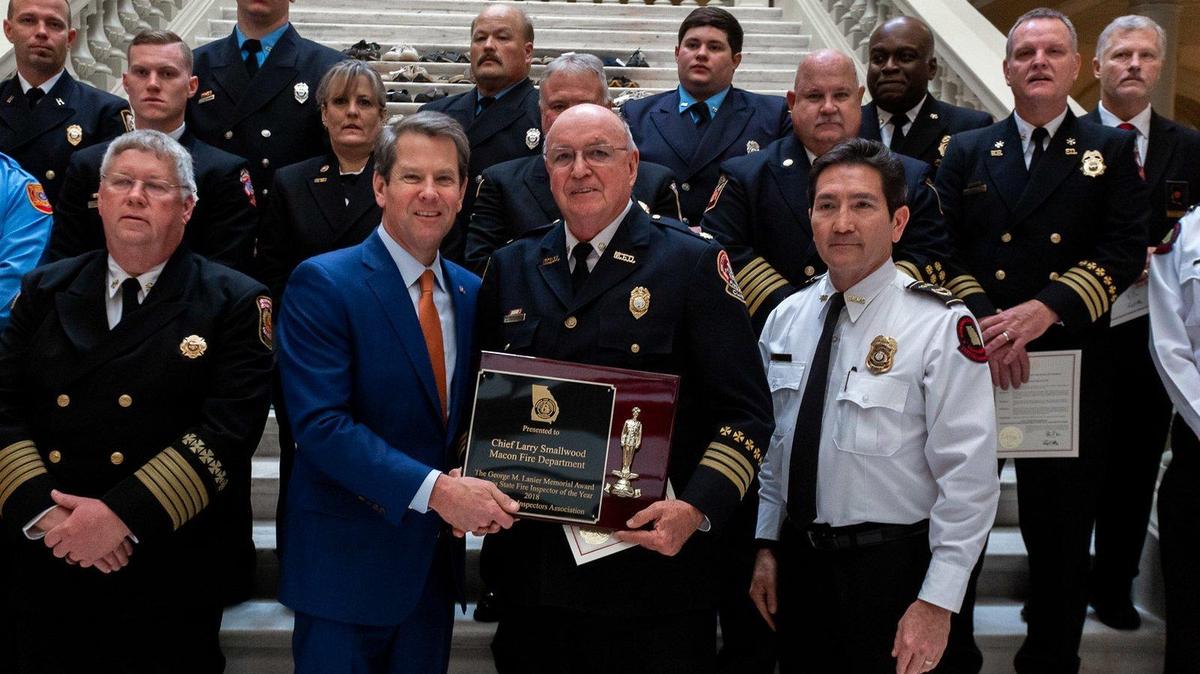 Larry Smallwood, the former chief of fire prevention at the Macon-Bibb County Fire Department, right center, receives the Georgia State Fire Inspector of the Year award from Governor Brian Kemp on Tuesday.