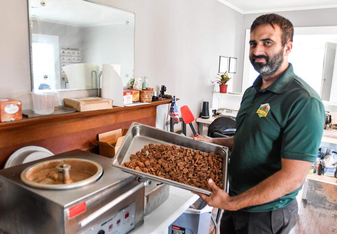 Tim Williams, owner of the Nut House Pecan Company at 106 Main St. in Byron, holds up a pan of praline pecans.
