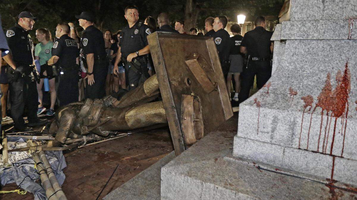 Police stand guard after the confederate statue known as Silent Sam was toppled Monday by protesters on campus at the University of North Carolina in Chapel Hill, N.C.