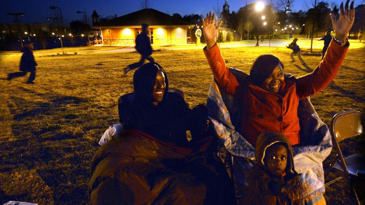 Anastasia Glover, right, celebrates her favorite team drawing first blood with a field goal in Super Bowl Fifty. Glover was watching the game in Tattnall Square Park wtih Trece Quainton and their five boys -- most of whom were playing football behind them.