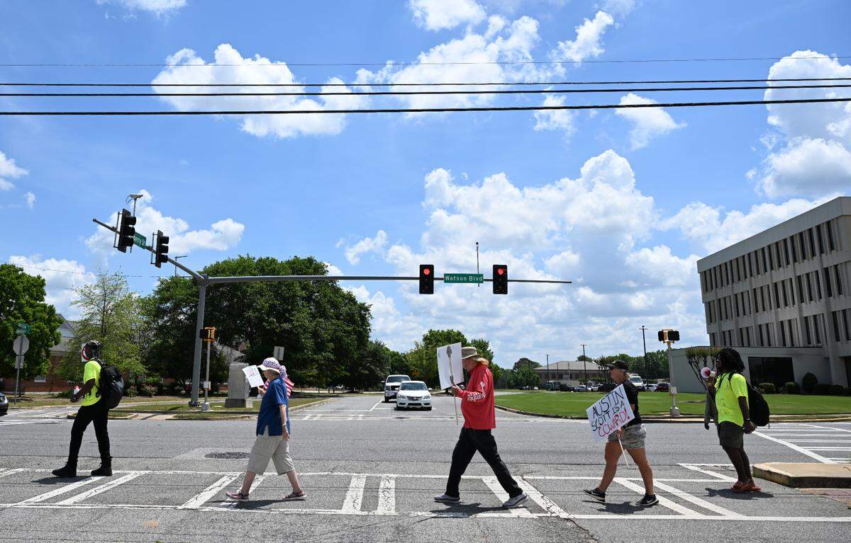 Protesters carry posters during a march down Watson Boulevard on Wednesday, April 30, 2025, in Warner Robins, Georgia. Around a dozen people gathered to protest against the Trump administration’s immigration policies.