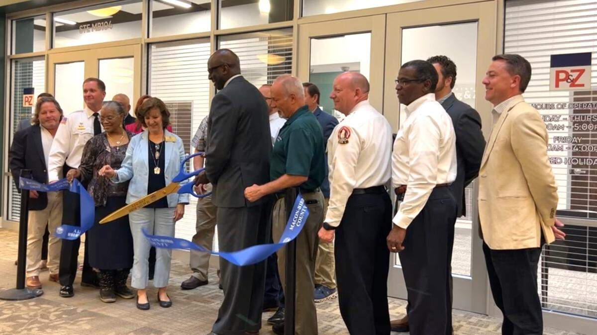 Dr. Keith Moffett, county manager cuts the ribbon at a ceremony on Monday for two new government offices that are now open in the Macon Mall.