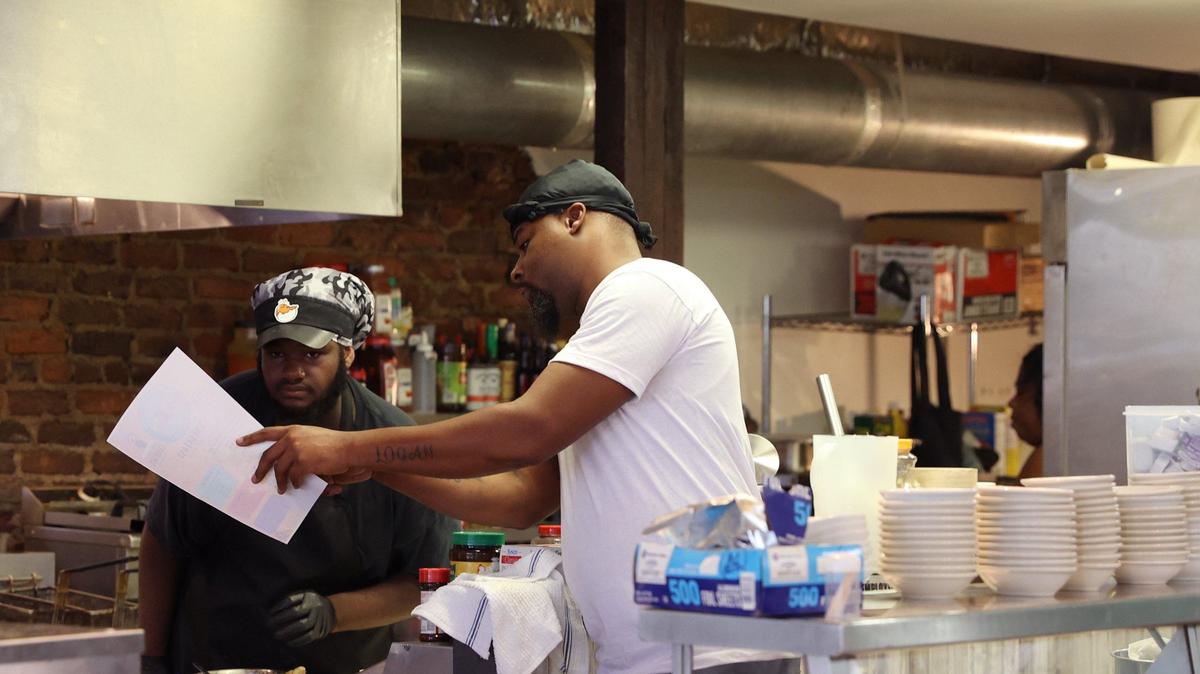 578 co-owner Xzavier Ottoman (right) speaks with Sherrod Williams on the first day of business at 578 Southern Style Cuisine on Friday, Oct. 4, 2024, in downtown Macon, Georgia. The new Macon soul food restaurant is open from early morning breakfast to late night dinner.