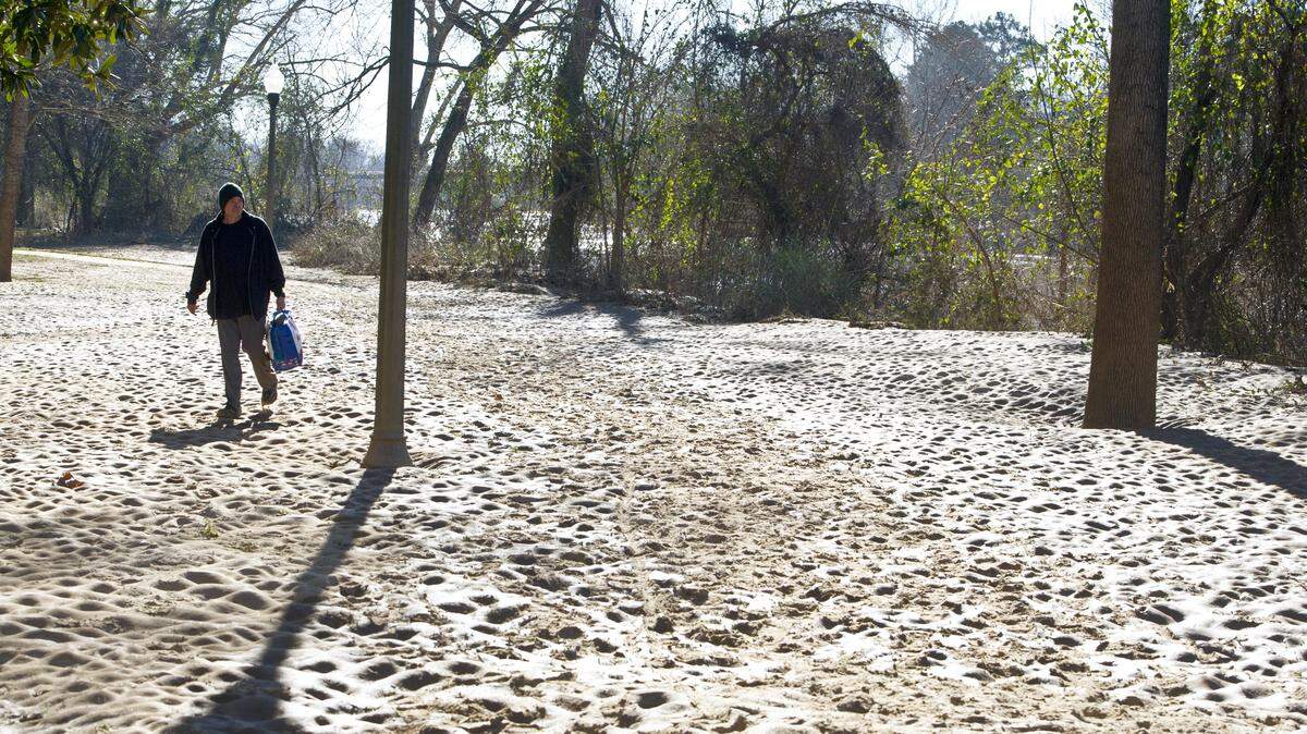 Michael Lynn walks along Ocmulgee Heritage Trail Monday morning across pile of sand left by December flooding.