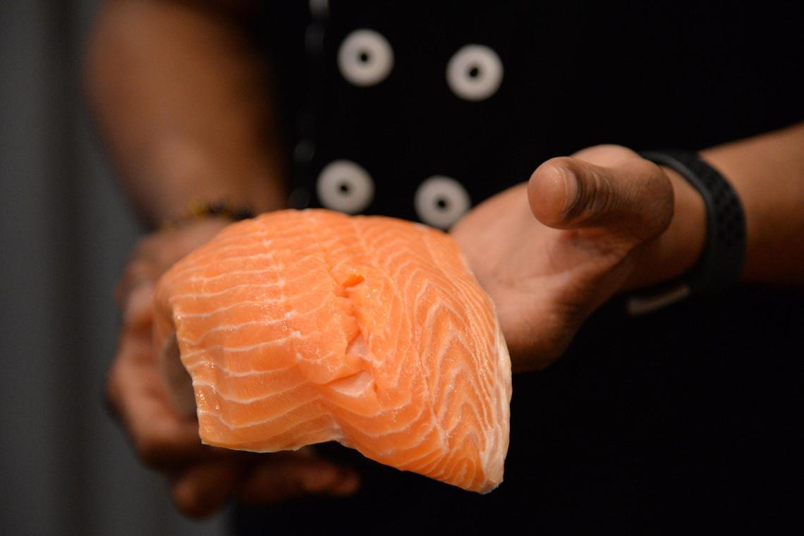 Chef Scottie Johnson, owner of Blessed and Highly Flavored Cuisine, holds up raw salmon that he is preparing to cook for the Hummel family on April 6. His business offers restaurant quality meals in an intimate home setting.