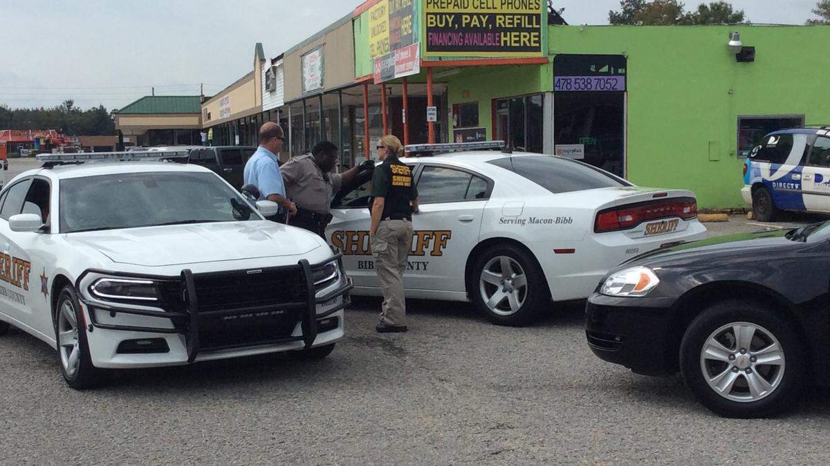 LIZ FABIAN/THE TELEGRAPH 
 Bibb sheriff's deputies compare notes after a reported forgeryTuesday morning at Kevin's Check Cashing on Pio Nono. The suspect got away after wrecking a vehicle during a chase on Interstate 75.
